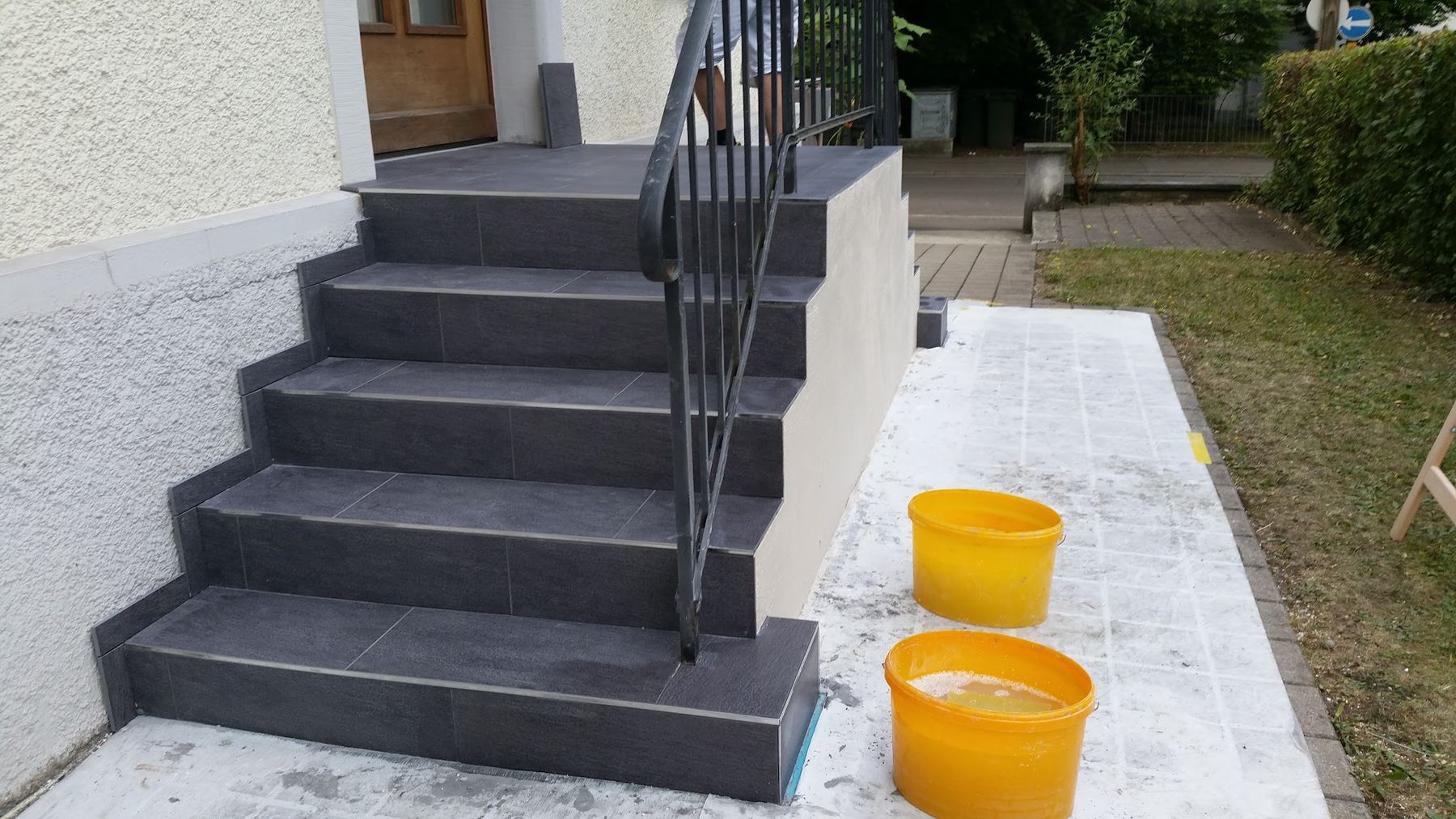 Aussentreppe und Podest mit dunklen Natursteinplatten und Geländer