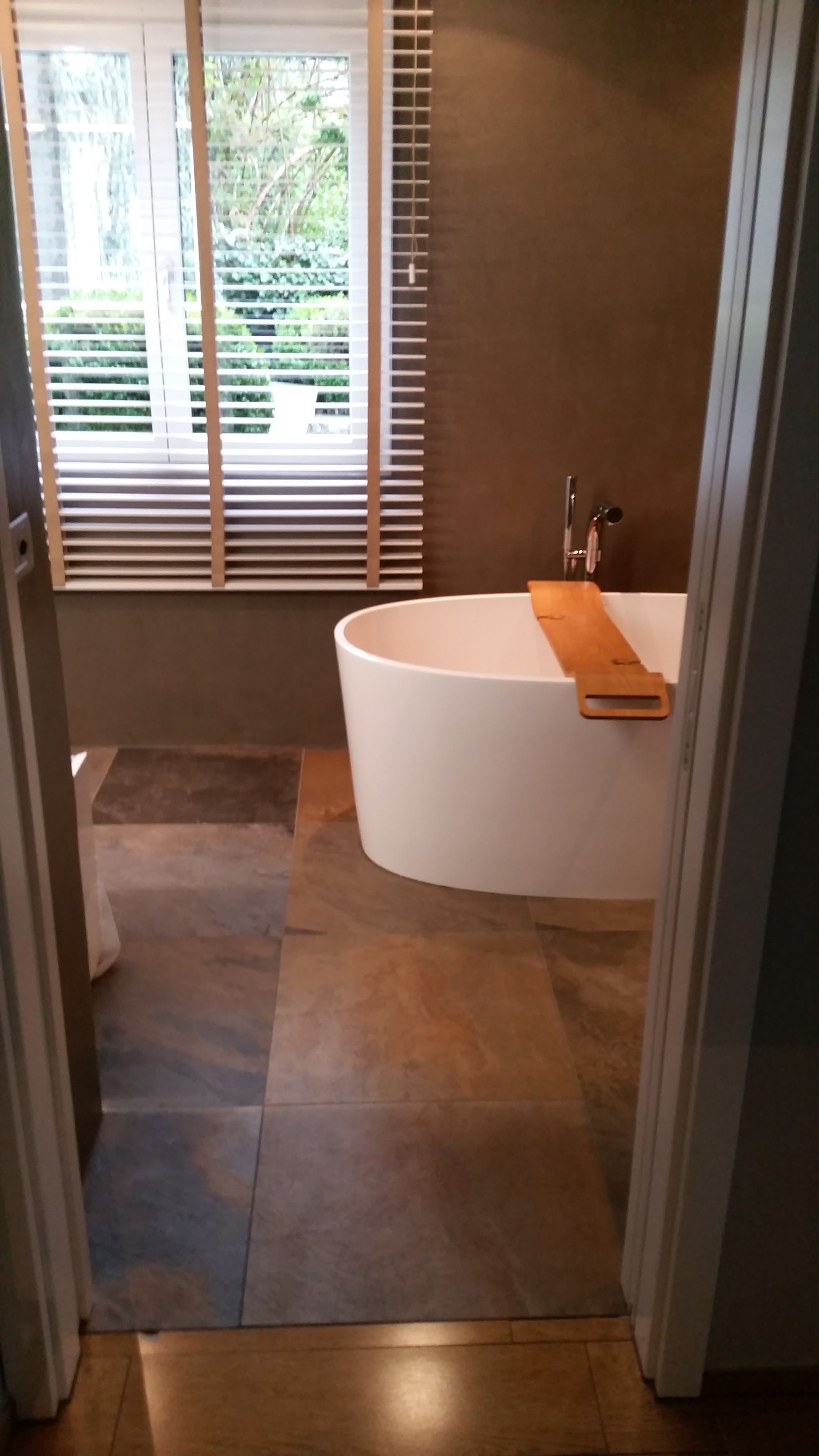 Badezimmer mit freistehender Wanne und dunklen Bodenfliesen